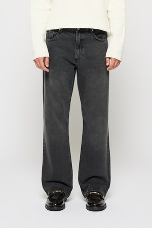 Zwarte wijde jeans met een vervaagd uiterlijk, voorzien van vijf zakken, een knoopsluiting en contrasterende stiksels op een effen achtergrond.