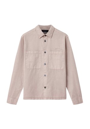 Vaaleabeige nappikiinnitteinen paita, valmistettu pehmeästä kankaasta, jossa on terävä kaulus, kaksi rintataskua ja mustat napit. Hienovarainen brändin kirjailu taskussa.
