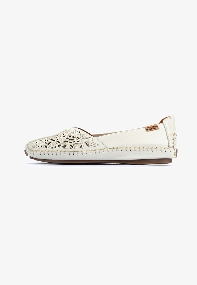 Chaussure slip-on beige clair avec un motif floral découpé complexe, tige en cuir, accents cousus et semelle flexible marron.