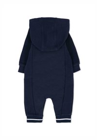 Granatowy kombinezon z kapturem o fakturowanym materiale, z prążkowanymi mankietami i kontrastowymi panelami bocznymi. Charakteryzuje się miękkim, wygodnym krojem i zapięciem na zamek.