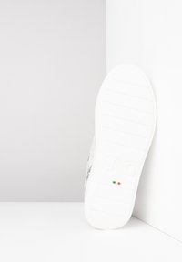 Sneaker blanche avec une tige texturée, dotée d'une semelle en caoutchouc lisse, de marquages subtils et d'un petit détail du drapeau italien près du talon.