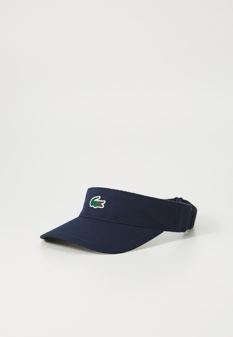 Mørkeblå solhatt laget av teksturert stoff, med en grønn og rød krokodille-logo foran og en justerbar stropp bak.