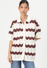 Cardigan a maglia con un motivo ondulato marrone e bianco, dotato di un collo e bottoni, realizzato in un materiale leggero e texture.