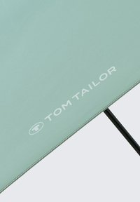 Green fabric umbrella with a smooth texture, featuring a black frame and a prominent white "TOM TAILOR" logo on the canopy.