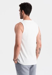 Débardeur en coton blanc avec un col ras du cou, sans manches et coupe décontractée. Il présente une texture lisse et arrive à la taille.