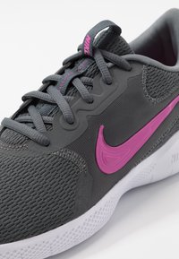 Nike-sneakers in grijs mesh met gestructureerde accenten, met een opvallende roze swoosh. Veters zijn grijs, met een gevoerde kraag voor comfort.