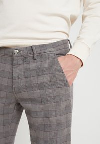 Grå rutiga byxor med ett texturerat mönster, som har knappstängning, sidfickor och en skräddarsydd passform.