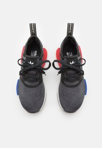 Athletic shoes with a dark gray knitted upper, black accents, red and blue plastic details, round toe, and black laces. Featuring branded pull tabs.