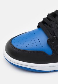 Baskets noires et bleues avec un dessus en cuir lisse, un boîtier de pied perforé, des lacets plats noirs et une semelle en caoutchouc blanche avec des accents bleus.