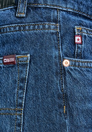 Mėlyni džinsai su matomomis siūlėmis, varinių smulkių detalių ir dviem etiketėmis: viena raudona ir viena su žvaigždės emblemą.