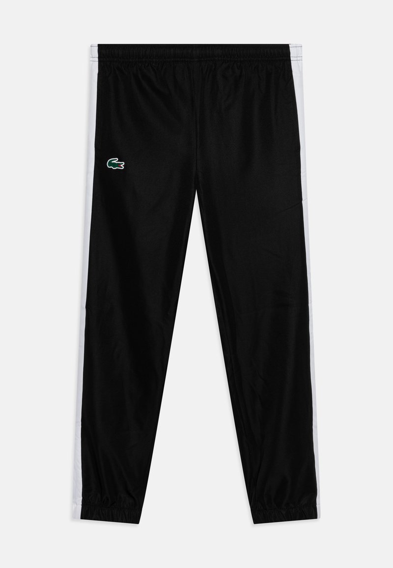 Pantalons de survêtement noirs en tissu léger, présentant des rayures blanches sur les côtés et un petit logo vert sur la cuisse gauche. Ceinture élastiquée.