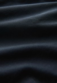 Material de culoare albastru închis, cu o textură netedă și un model subtil de nervuri, prezentând pliuri moi, fluide și un ușor strălucire.