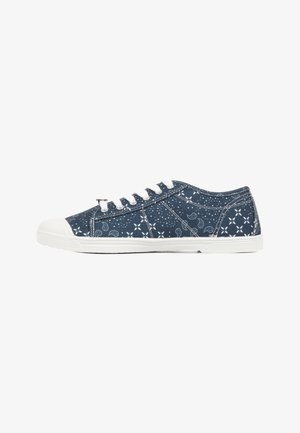 Zapatilla deportiva de corte bajo azul marino con patrones florales y de puntos blancos, cordones blancos, puntera de goma blanca y suela blanca.
