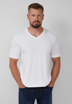 Biała koszulka V-neck z miękkiego materiału, krótkie rękawy, z delikatnym streczem. Posiada subtelne logo w okolicy klatki piersiowej oraz luźny krój.