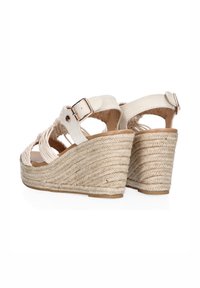 Sandalias de cuña blancas con un tacón de yute trenzado, que cuentan con la punta abierta y una correa para el tobillo con un hebilla dorada. Superficie texturizada y forro suave.