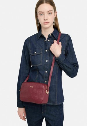Borsa a tracolla color mogano in pelle testurizzata, con logo impresso, hardware dorato e tracolla regolabile.