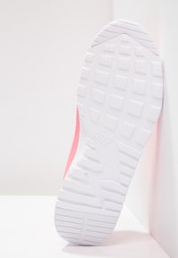 Nike-sneaker med en rosa ovandel, vit texturerad gummisula och vinkelräta mönster för förbättrat grepp.