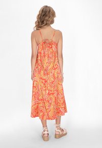 Blumendruck, rückenfreies Kleid mit Spaghettiträgern in leuchtenden Orange-, Gelb- und Pinktönen. Verfügt über einen lockeren Schnitt und einen fließenden Saum.