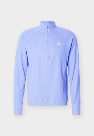 Lichtblauwe pullover met lange mouwen, kwartrits en klein wit driehoekig logo op de linkerborst.