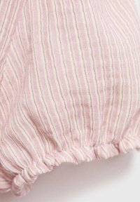 Světlé růžové látky s vertikálními bílými pruhy, s nařasenným lemem. Textura vypadá měkce a mírně zmačkaná.