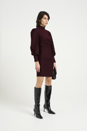 Burgundy fitted dress with long puff sleeves, paired with high-gloss black knee-high heeled boots. Simple design, minimal detailing.