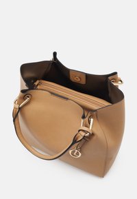 Sac en cuir marron texturé avec des accents noirs, des finitions dorées, un intérieur spacieux et un compartiment zippé.