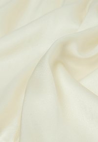 Tela de seda en un suave color blanco roto, con una textura lisa y un ligero brillo, que presenta suaves pliegues y una caída fluida.