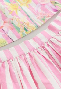 Tela con estampado floral en colores pastel con rayas rosas y blancas. Textura fruncida en el dobladillo, material de algodón ligero.