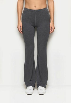 Graue, dehnbare Schlaghosen mit einem elastischen Bund, die eine glatte Textur und eine saubere Naht auf der Vorderseite aufweisen. Weiße Sneakers darunter.