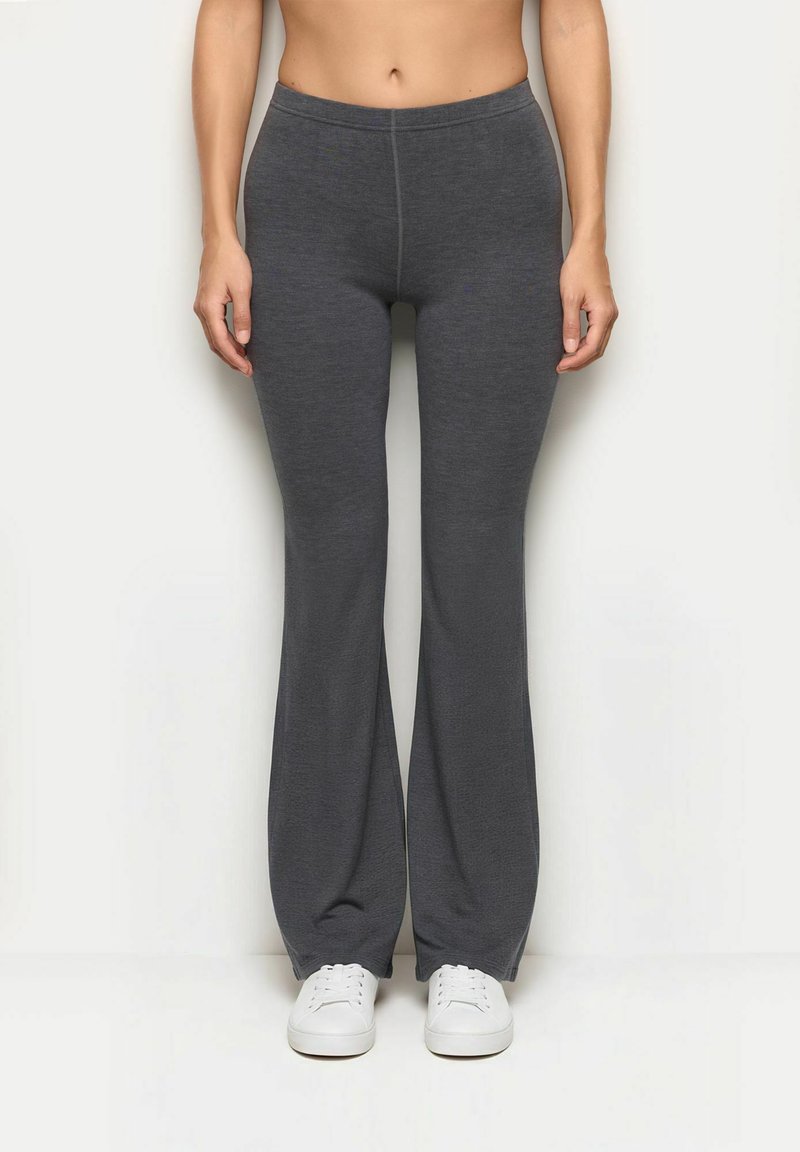 Szare, elastyczne spodnie z rozszerzanymi nogawkami i elastycznym pasem, z gładką teksturą i czystym szwem z przodu. Białe sneakersy na dole.