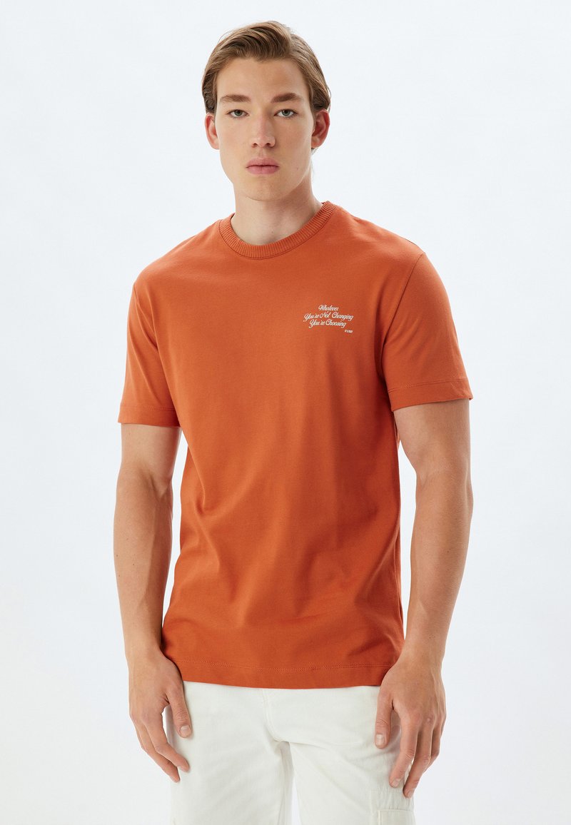 Herre kortærmet orange bomulds t-shirt med rund halsudskæring og hvid tekstdetalje på brystet. Glat tekstur, almindelig pasform.