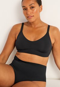 Svart bralette och hög midja underkläder set i mjukt tyg. Har justerbara axelband och sömlös design för komfort.
