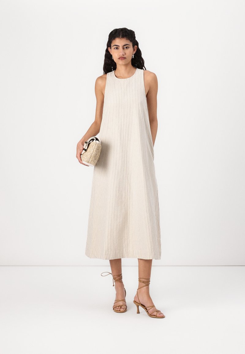 Hellbeige ärmelloses Kleid mit vertikalen Streifen, knöchellang, kombiniert mit hellbraunen Riemchenschuhen und einer kleinen geflochtenen Handtasche.