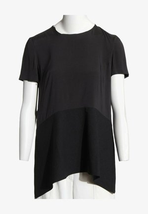 Tunique noire à manches courtes avec ourlet asymétrique présentée sur un buste de mannequin blanc sur fond blanc.