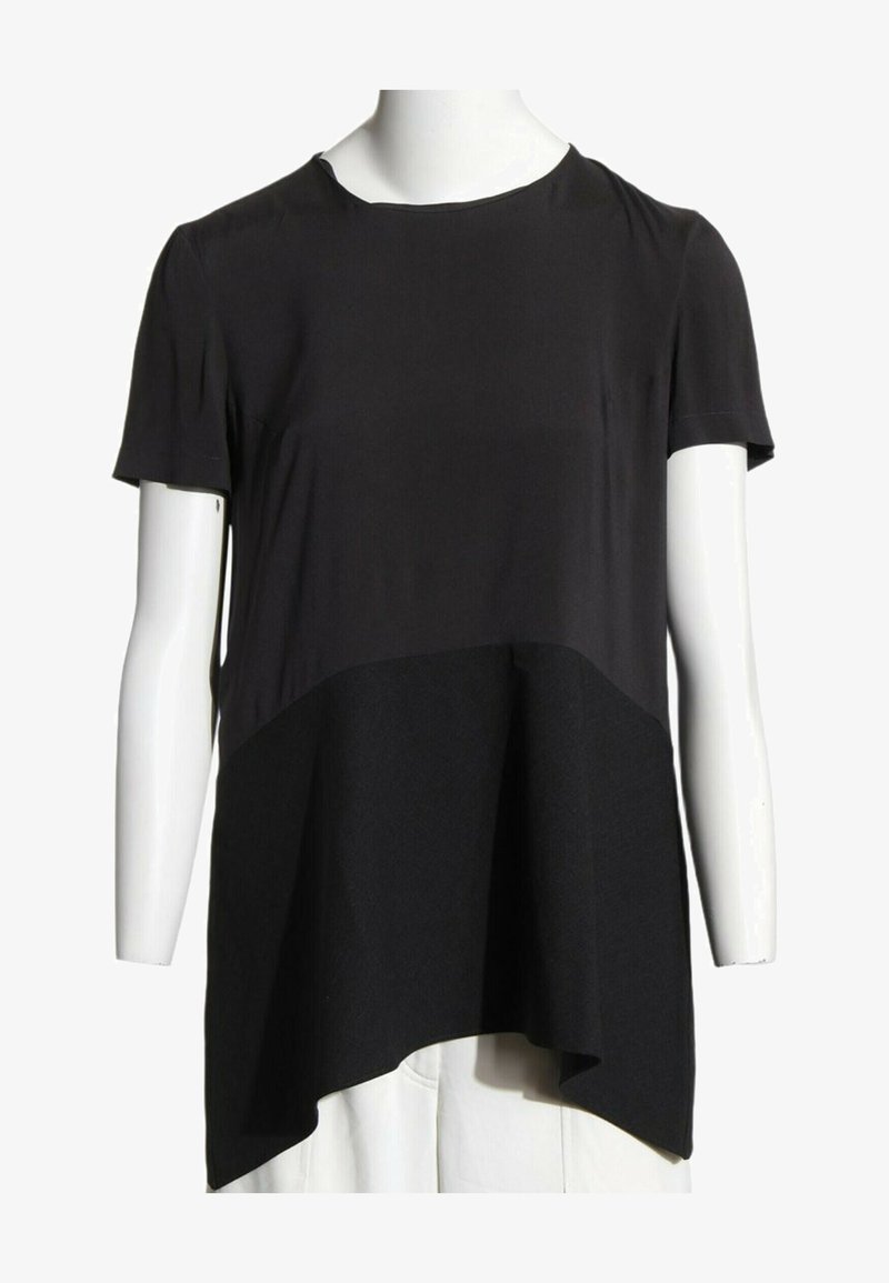 Tunique noire à manches courtes avec ourlet asymétrique présentée sur un buste de mannequin blanc sur fond blanc.