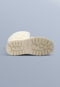 Białe ocieplane śniegowce z teksturowaną gumową podeszwą, charakteryzujące się rowkowanym wzorem dla lepszej przyczepności i lekko wygiętym noskiem.