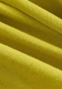 Tela de punto amarilla con una textura suave, que presenta pliegues diagonales y un patrón de tejido fino y uniforme en toda la superficie.