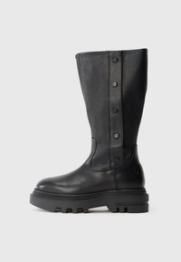 Bota de cuero negra hasta la rodilla con suela de goma gruesa y cuatro botones decorativos a lo largo del panel lateral texturizado.