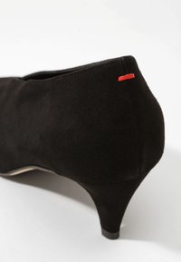 Chaussure à talon haut en daim noir avec un talon conique effilé. Présente un petit accent rouge près du talon et une texture lisse et mate.