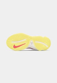 Semelle en caoutchouc jaune d'une chaussure de sport avec le swoosh rouge de Nike et des motifs de bande de roulement sur fond blanc.