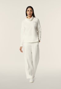 Set di abbigliamento da tempo libero bianco in tre pezzi che include una felpa con collo a cowl morbido e pantaloni a gamba larga, entrambi con sottili accenti di branding.