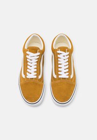 Suede sneakers i sennepsgult med hvite snører og sidestropper. Har en rund tå og svart gummisåle for kontrast.