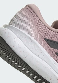 Nahaufnahme der Ferse eines mauvefarbenen Mesh-Sneakers mit weiß gesprenkelter Mittelsohle und schwarzem, strukturiertem Außensohlenprofil.