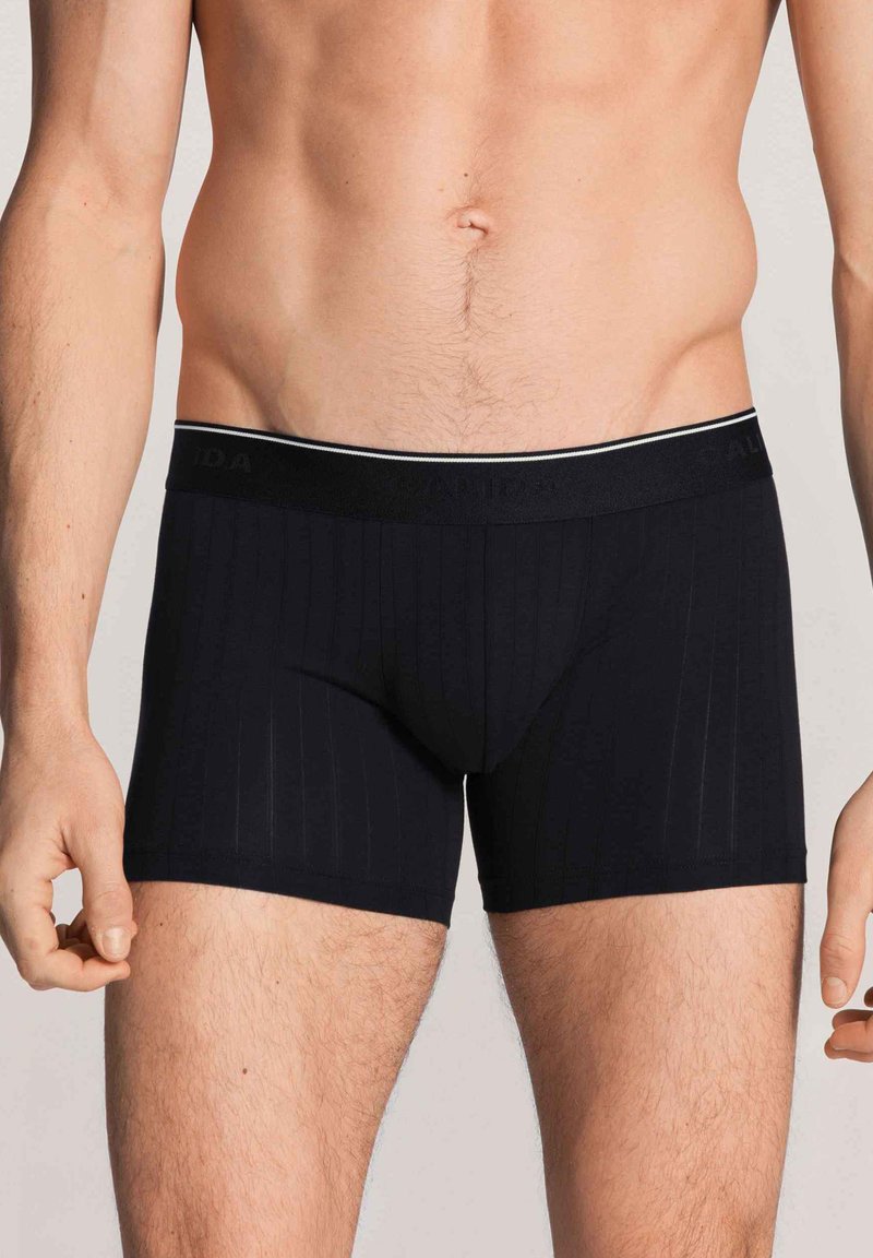 Zwarte boxershorts voor mannen met verticale strepen, een elastische tailleband met een contrasterende afwerking en een gladde textuur.