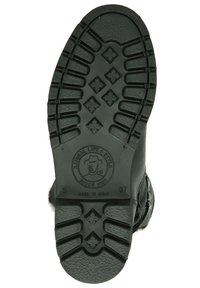 Suela de bota de goma negra con un diseño texturizado y patrones de diamante, logo circular y marcas de tamaño en relieve. Fabricada en España.