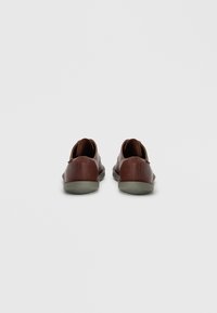 Καφέ δερμάτινα παπούτσια με λεία επιφάνεια, στρογγυλεμένο σχήμα, μινιμαλιστικό σχέδιο και ανοιχτό γκρι λαστιχένιες σόλες. Χωρίς ορατά μεταλλικά στοιχεία ή σχέδια.