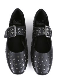 Zapatos de cuero sintético negro con punta redondeada, adornados con remaches metálicos y una correa ajustable con una hebilla plateada.