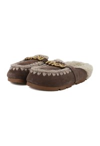 Pantofole slip-on in suede marrone con fodera in shearling, accent in treccia e lettere dorate. Suola piatta in gomma con dettagli decorativi a cucitura.