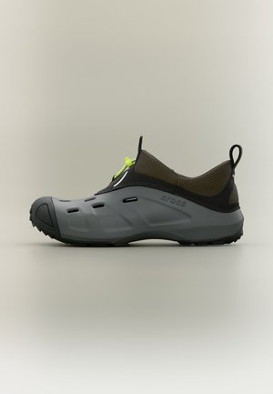 Sportlicher Slip-On-Schuh mit grauer Gummisohle, braunem Mesh-Obermaterial, schwarzen Akzenten, Belüftungslöchern und neongrünem Zugverschluss.