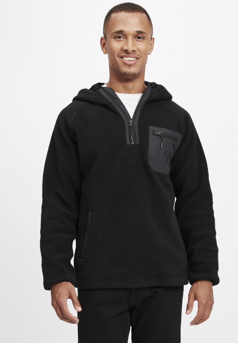 Czarny polarowy hoodie z suwakiem, z przednią kieszenią i teksturowanym materiałem. Posiada kaptur i kieszenie boczne.